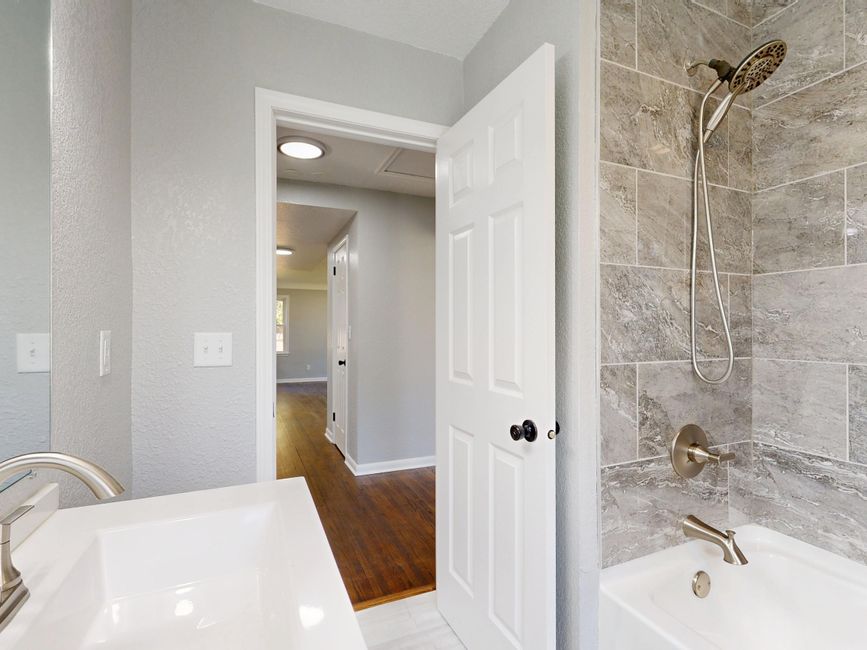 Contemporary bathroom featuring a grey tile shower and sleek fixtures.